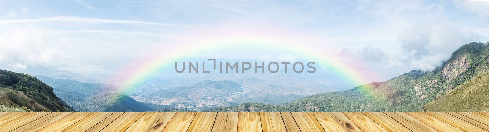 Empty wooden table top and blurred view of rainbow at lanscape mountain background, For display of your product, Raining day in nature with table top background