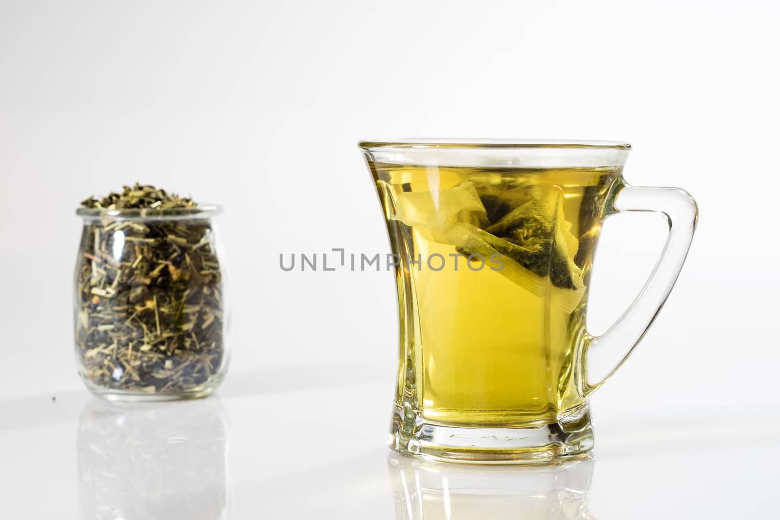 Tea in a glass on a white background. Green or fruit tea. Glass of white glass