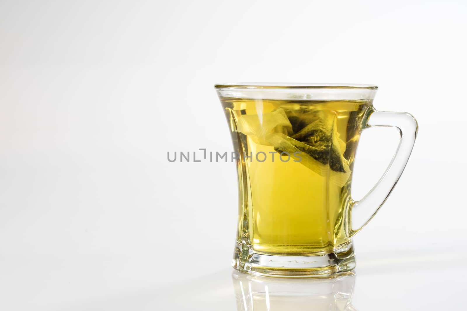 Tea in a glass on a white background. Green or fruit tea. Glass of white glass