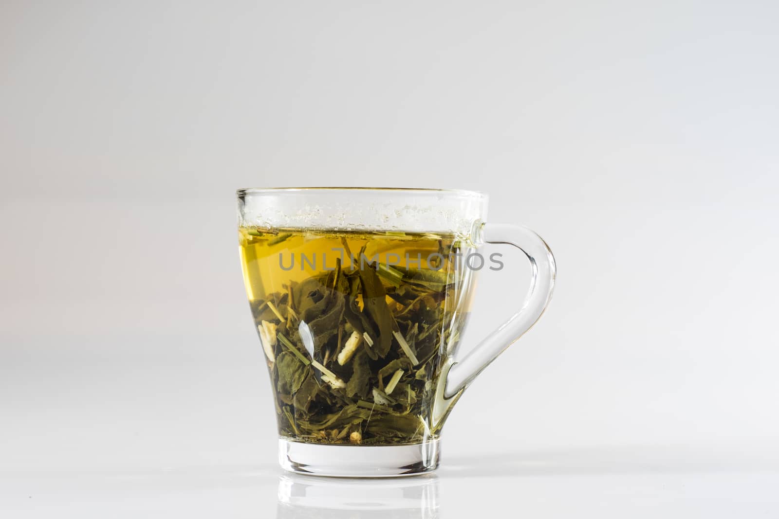 Tea in a glass on a white background. Green or fruit tea. Glass of white glass