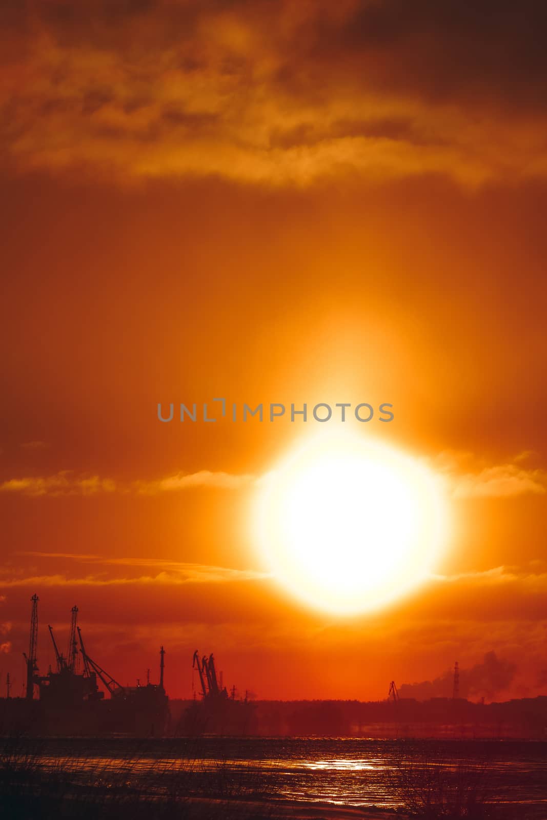 Hot orange winter sunrise against the cargo port