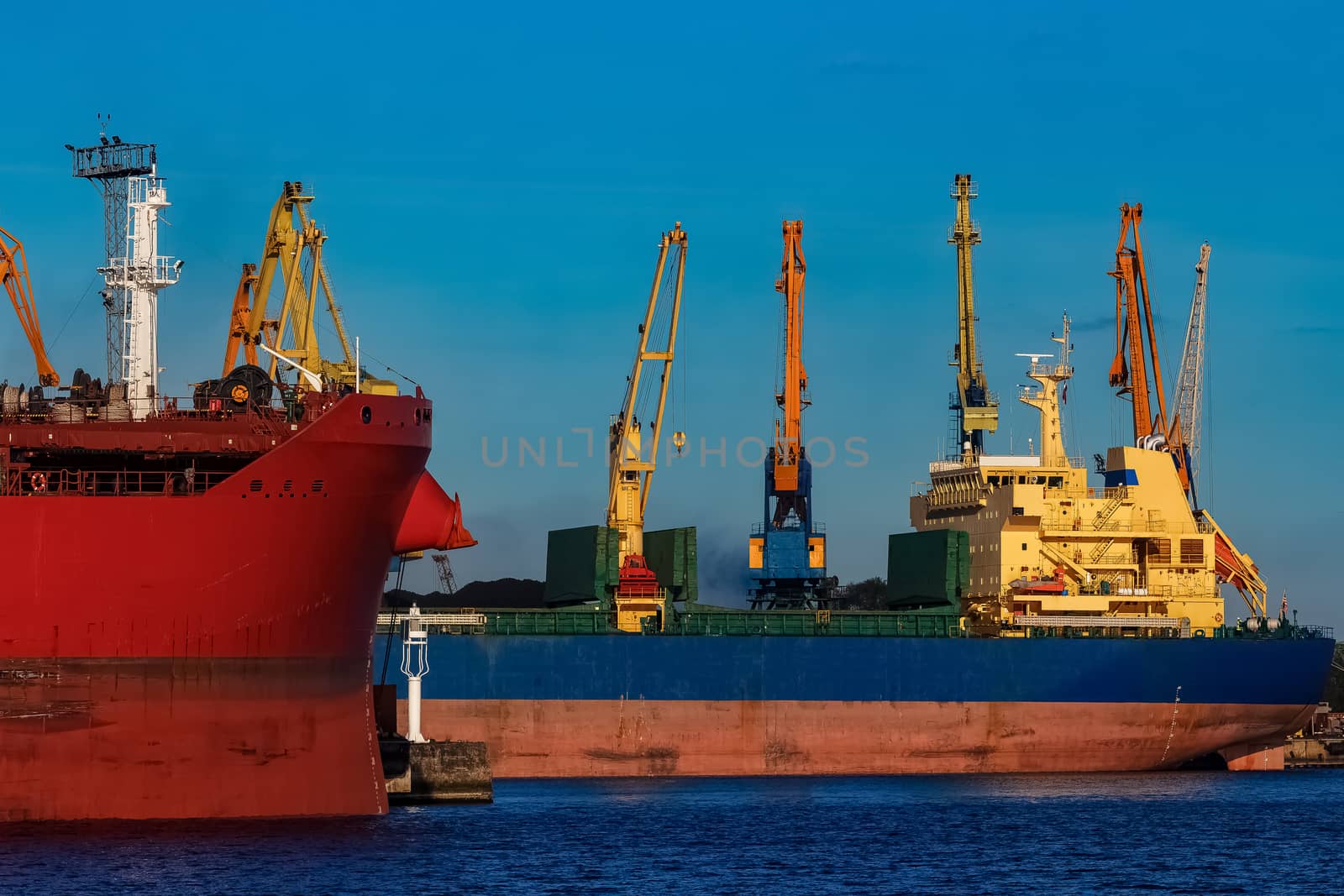 Red and blue cargo ship loading in the port of Riga