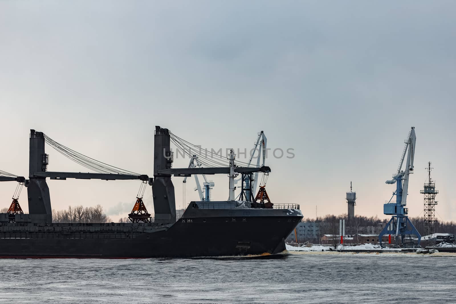 Black bulk carrier sailing to the sea in cold winter