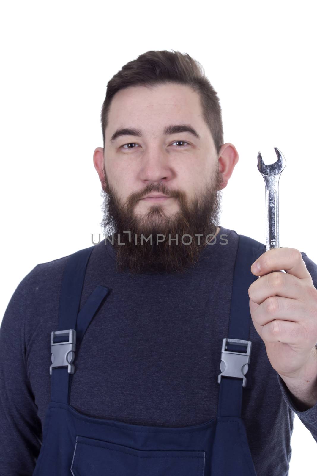 Bearded young man with a wrench in a working overall