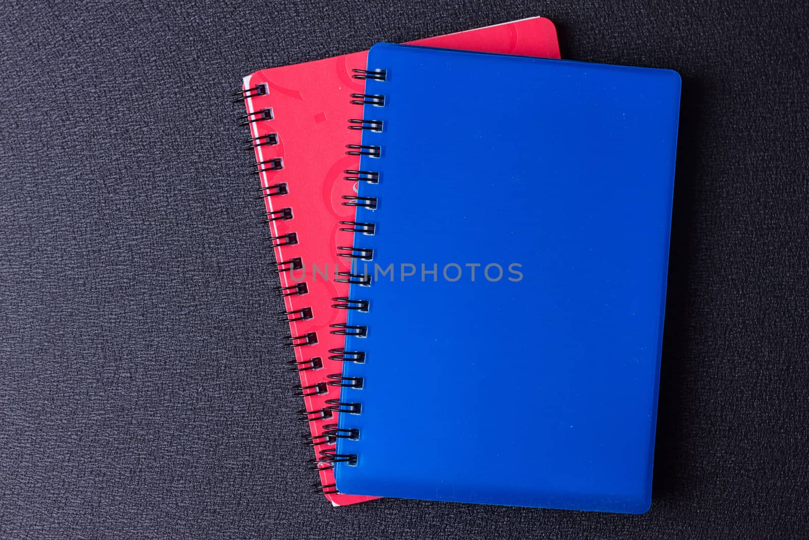 Several multi-colored notebooks on a spiral on a black background