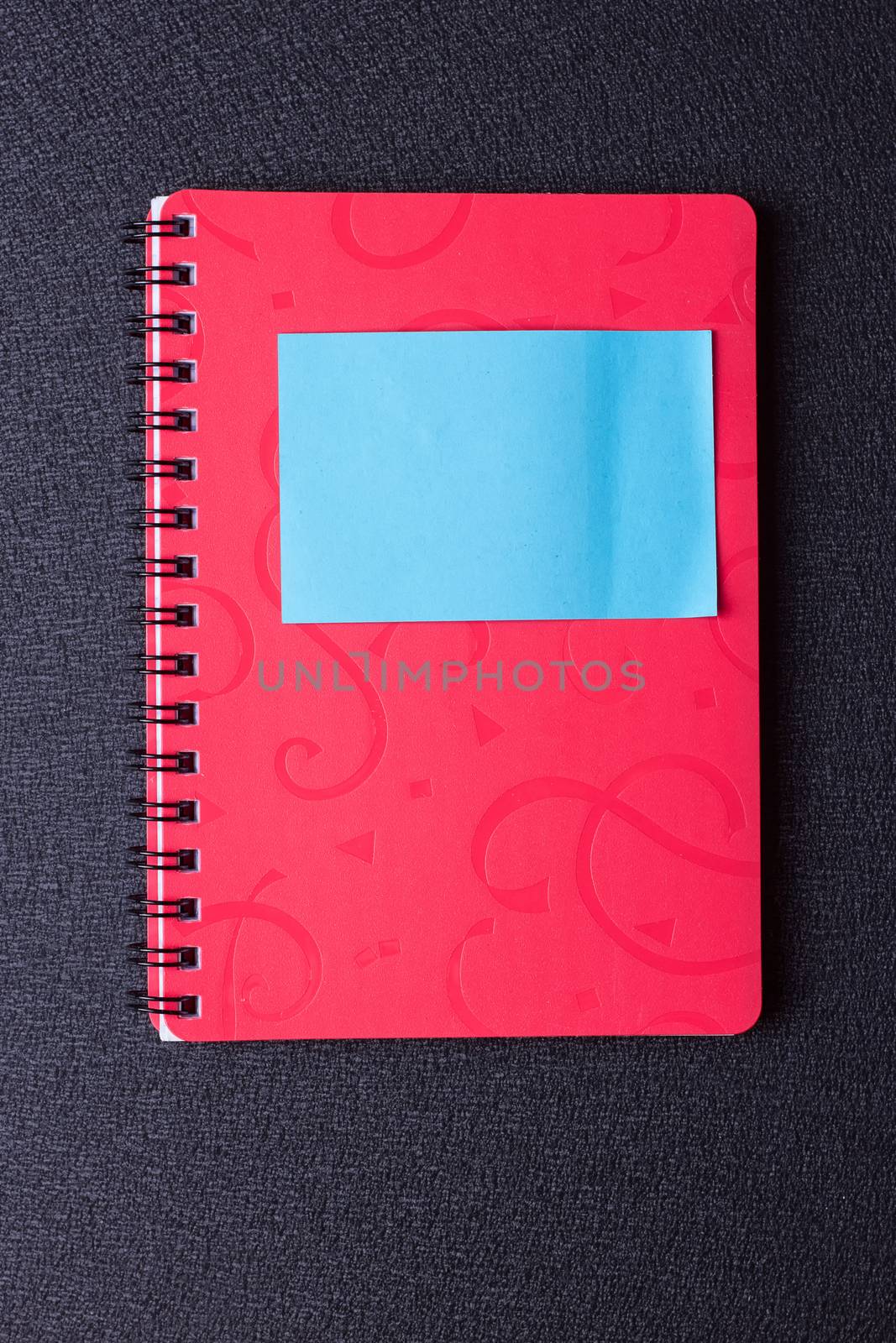 Red notepad on a spiral with a sticker on a black background