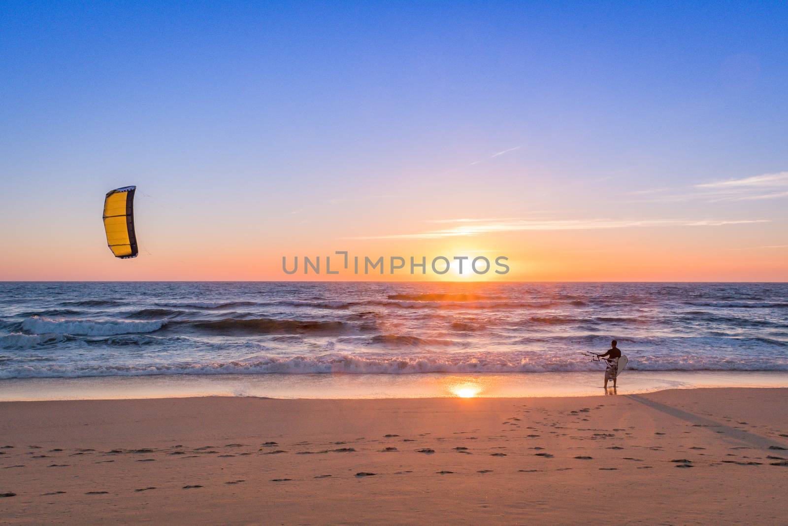 Kite surfer watching the waves at sunset in Portugal.