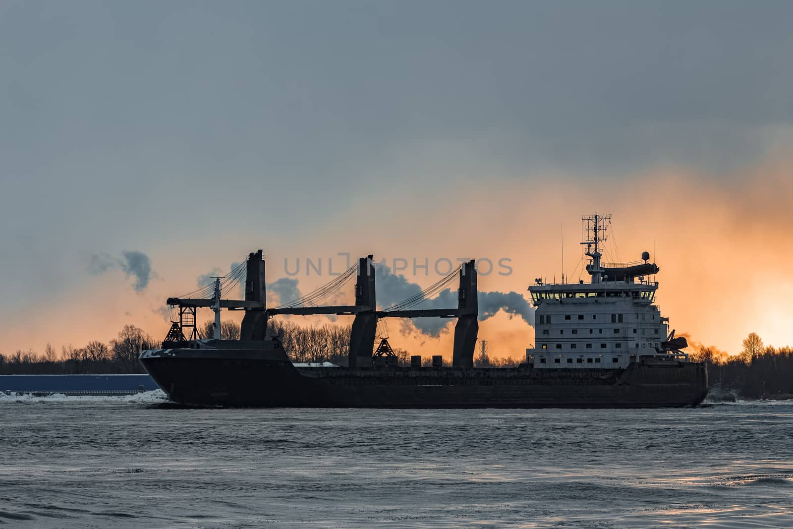 Black bulk carrier sailing to the sea in cold winter