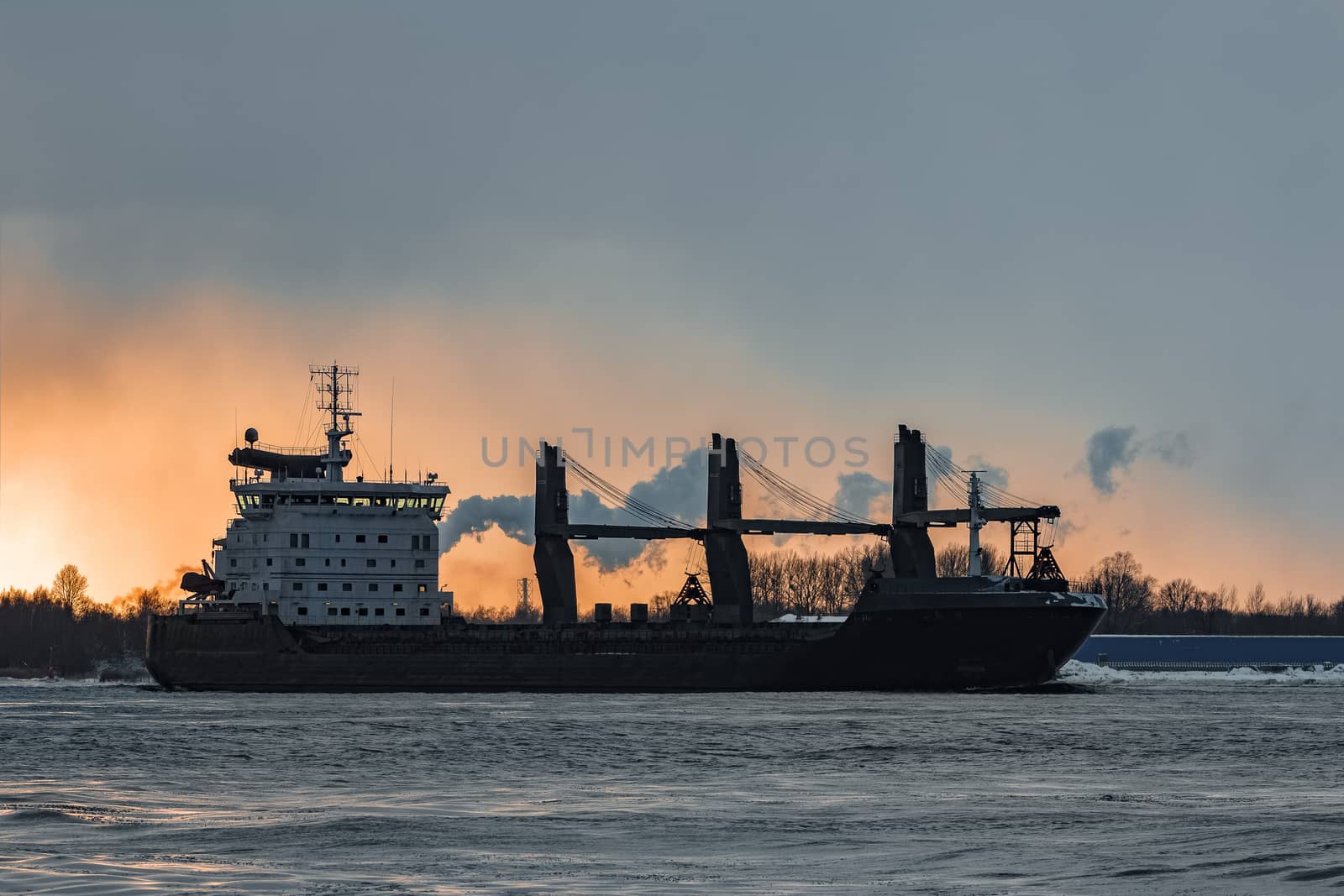 Black bulk carrier sailing to the sea in cold winter