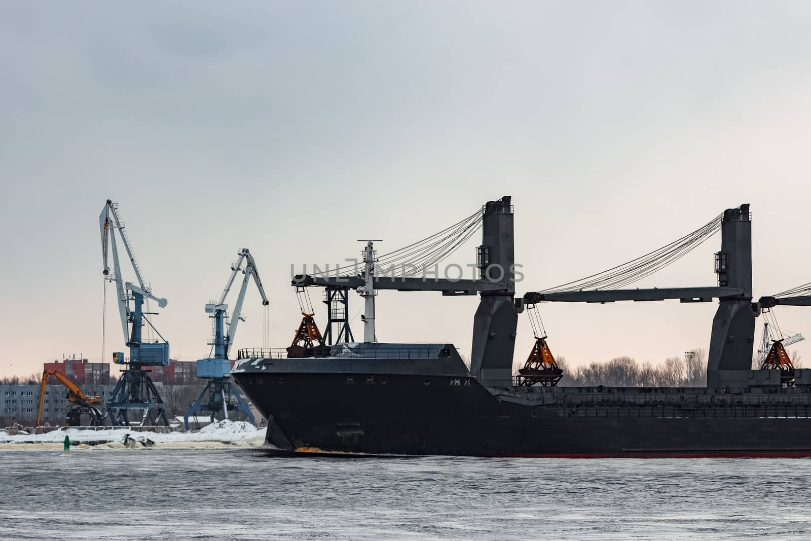 Black bulk carrier sailing to the sea in cold winter