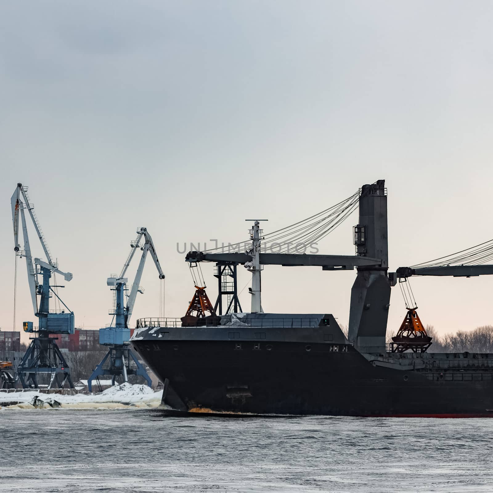 Black bulk carrier sailing to the sea in cold winter