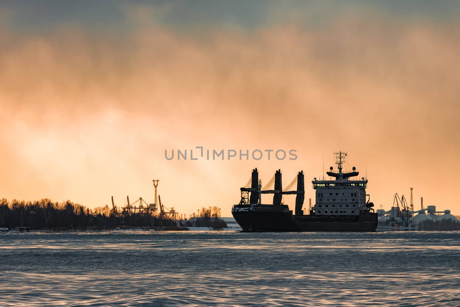 Black bulk carrier sailing to the sea in cold winter