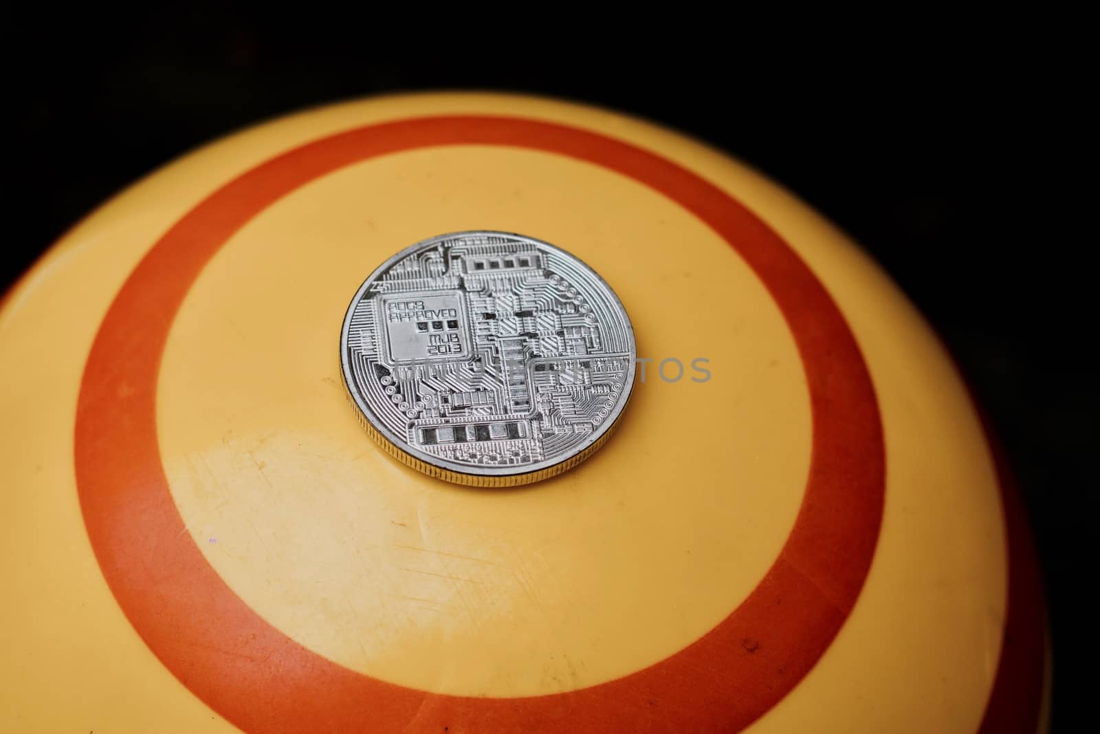 Digital currency physical silver bitcoin coin on yellow circle background.