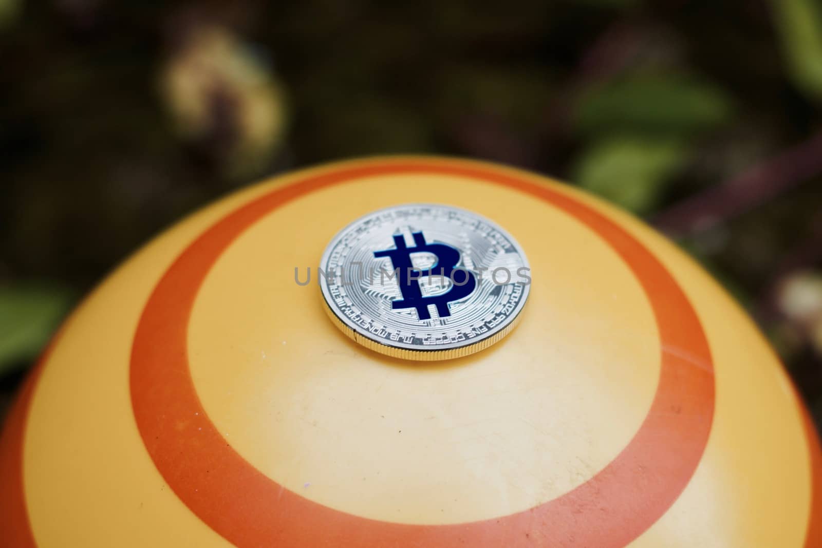 Digital currency physical blue bitcoin coin on yellow circle background.