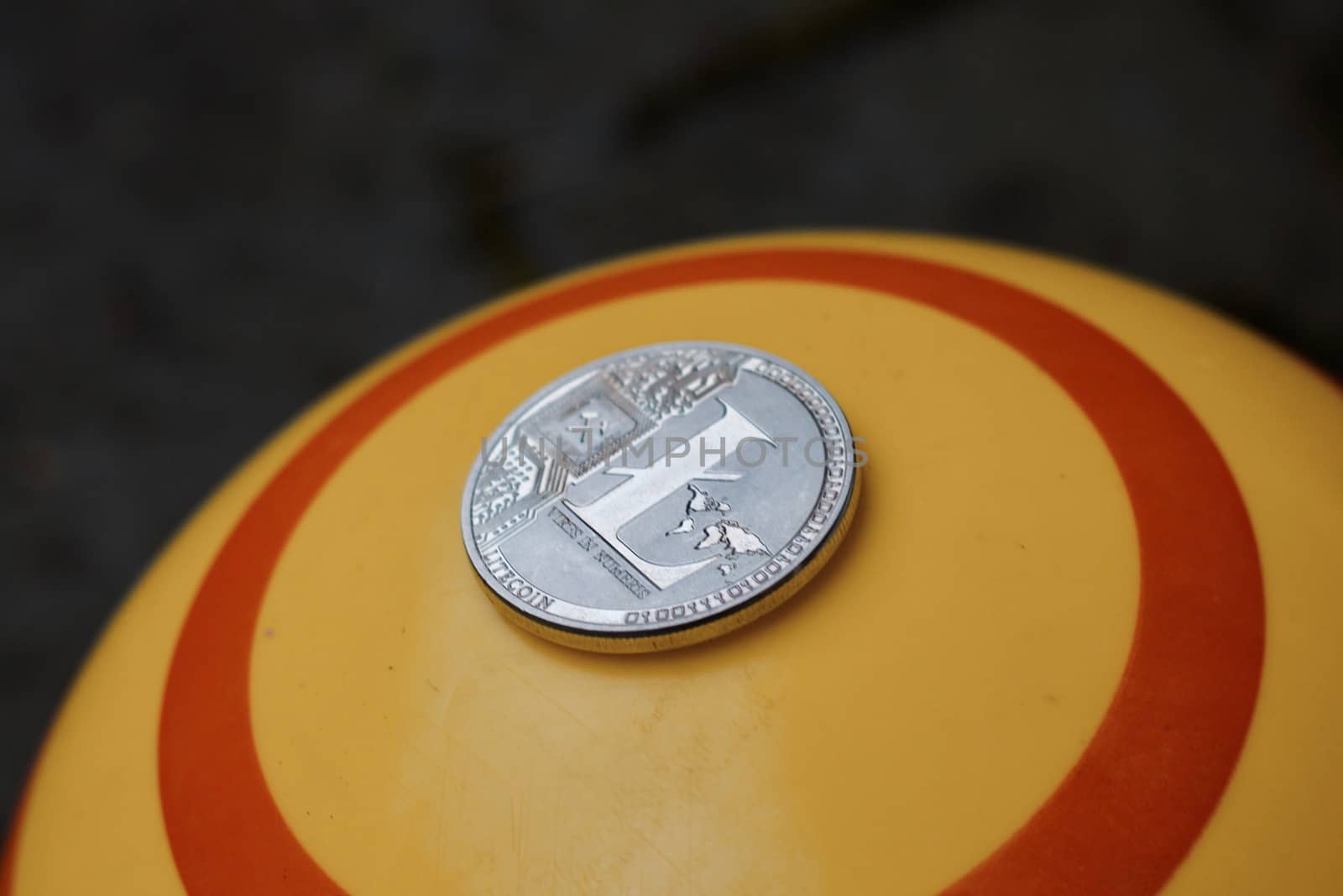 Digital currency physical silver litecoin coin on yellow circle background.