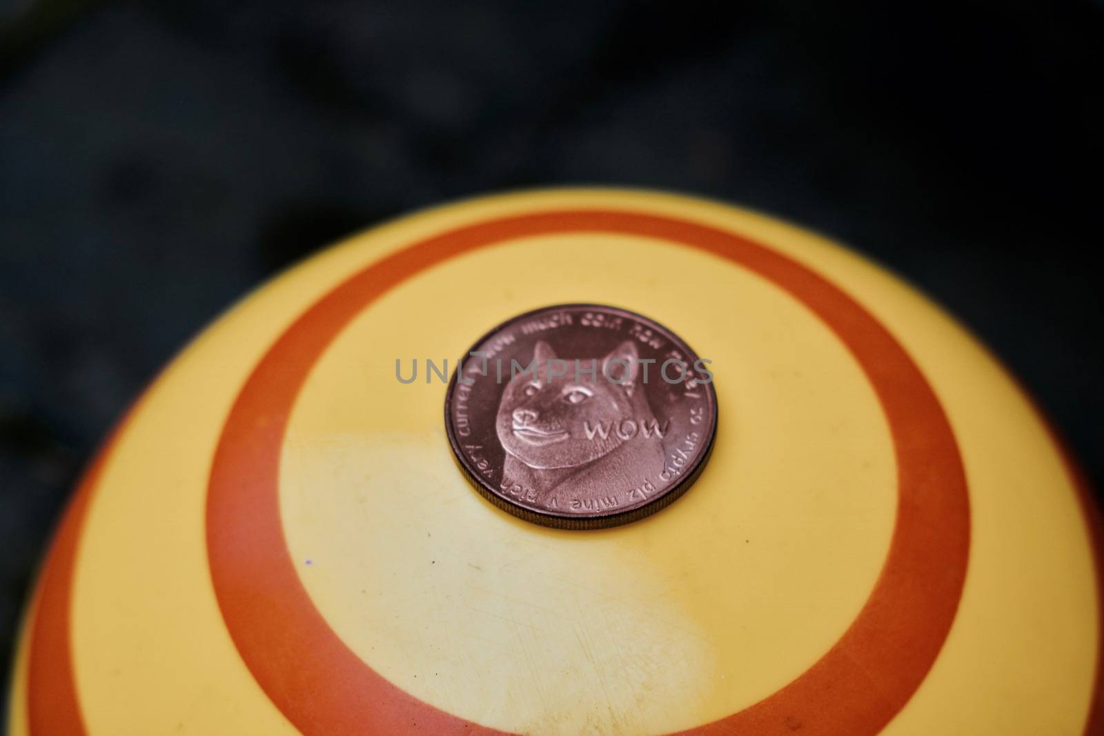 Digital currency physical brass dogecoin coin on yellow circle background.