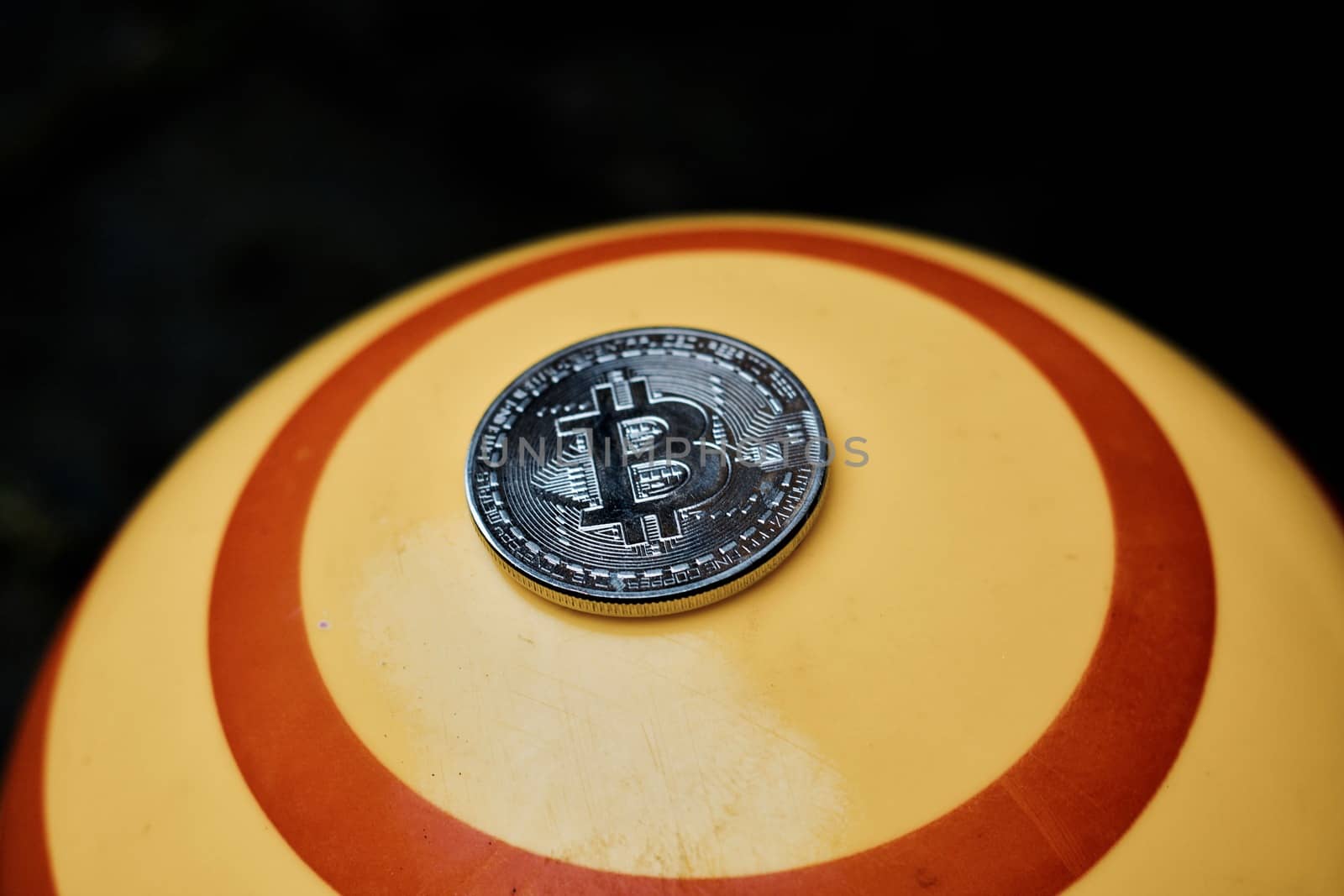Digital currency physical silver bitcoin coin on yellow circle background.