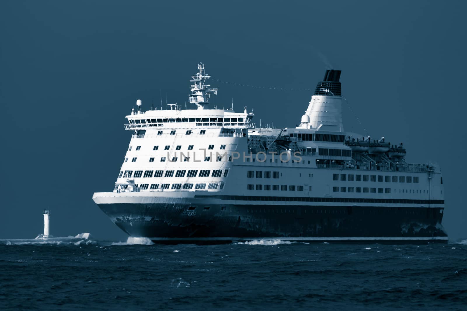 Passenger ship sailing from the sea in the morning. Toned dark blue