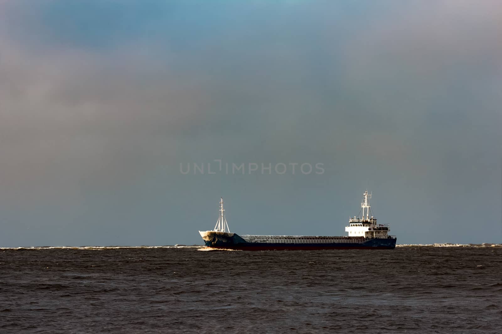 Blue bulk carrier moving from the sea in cold winter