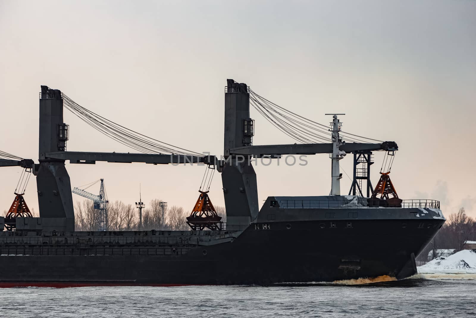 Black bulk carrier sailing to the sea in cold winter