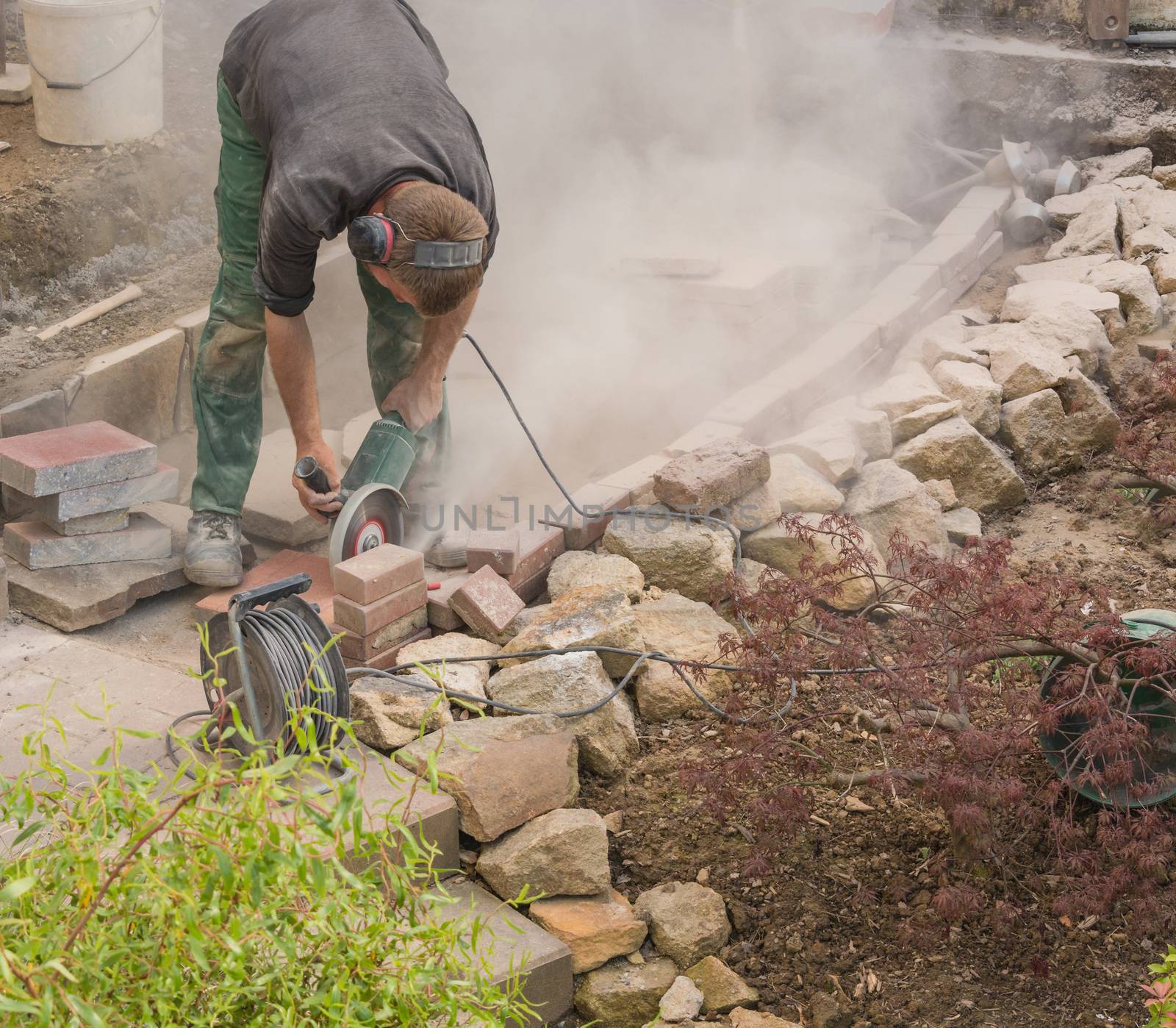 Man cutting stone slabs, concrete slab with an electric grinder