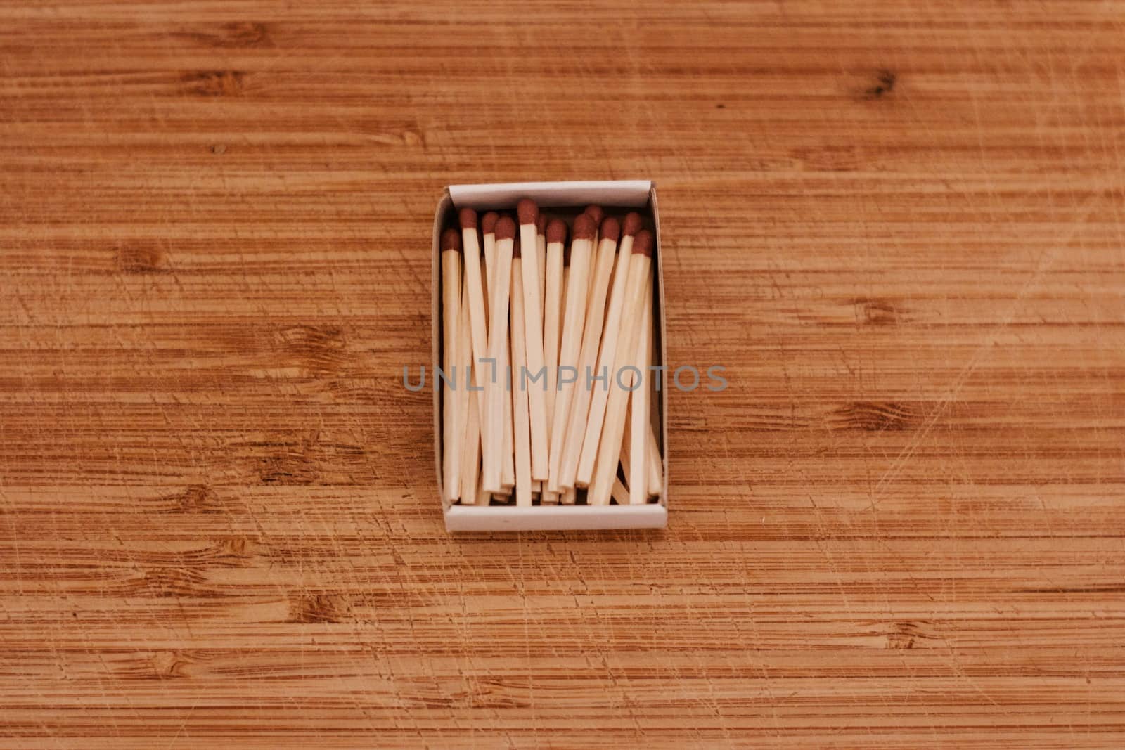 Small wooden matches in a box on the wooden board. Closeup photography.