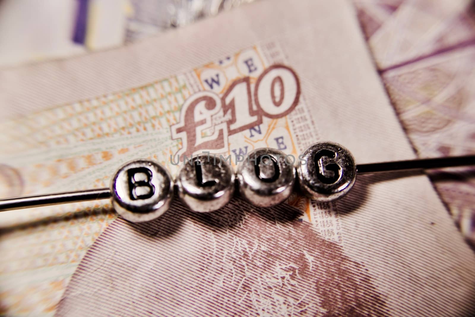 Small blog silver letters on ten pounds money background.