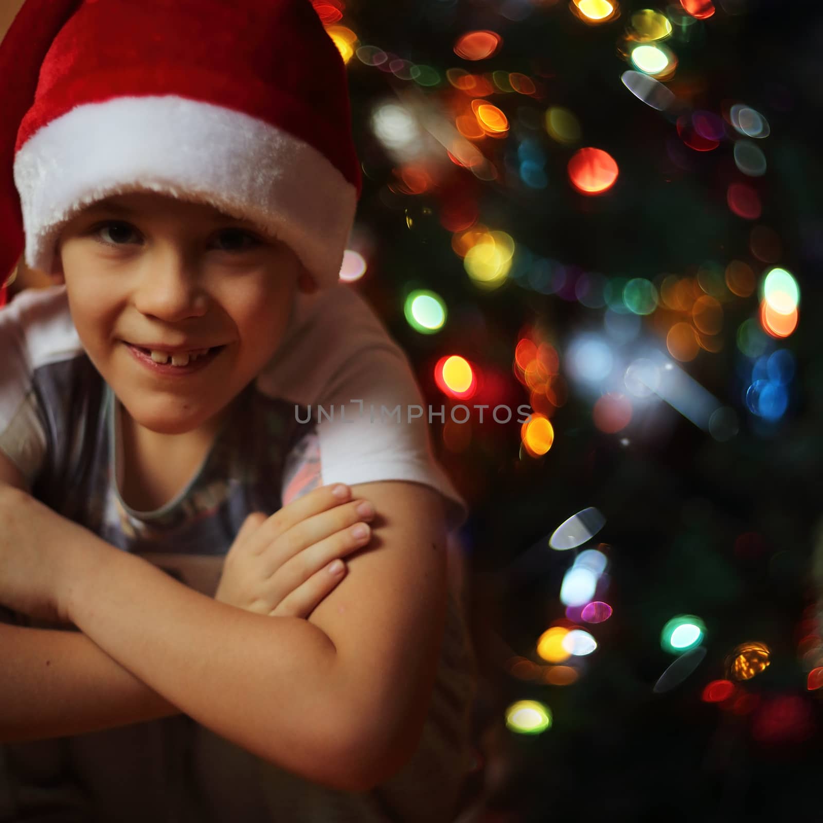 Happy little boy sitting near decorated christmas tree