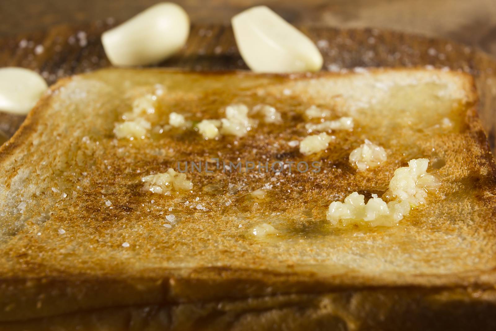 Roasted garlic bread close-up, and cloves of fresh garlic