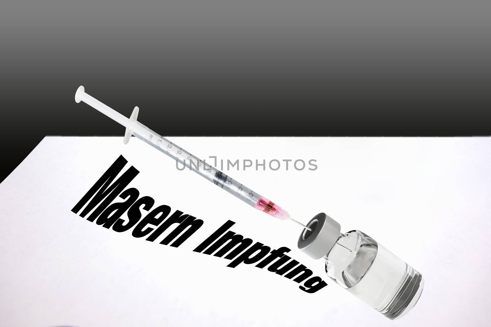 Close-up view, a syringe and a bottle with medical fluid. Lettering in German "Measles vaccination"