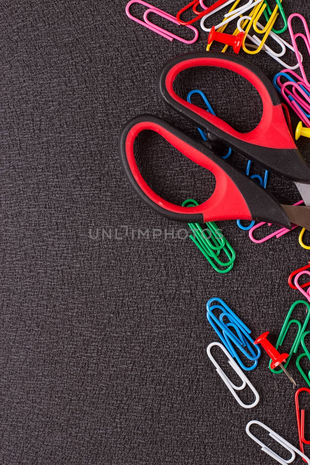 Scissors and paper clips on a black background