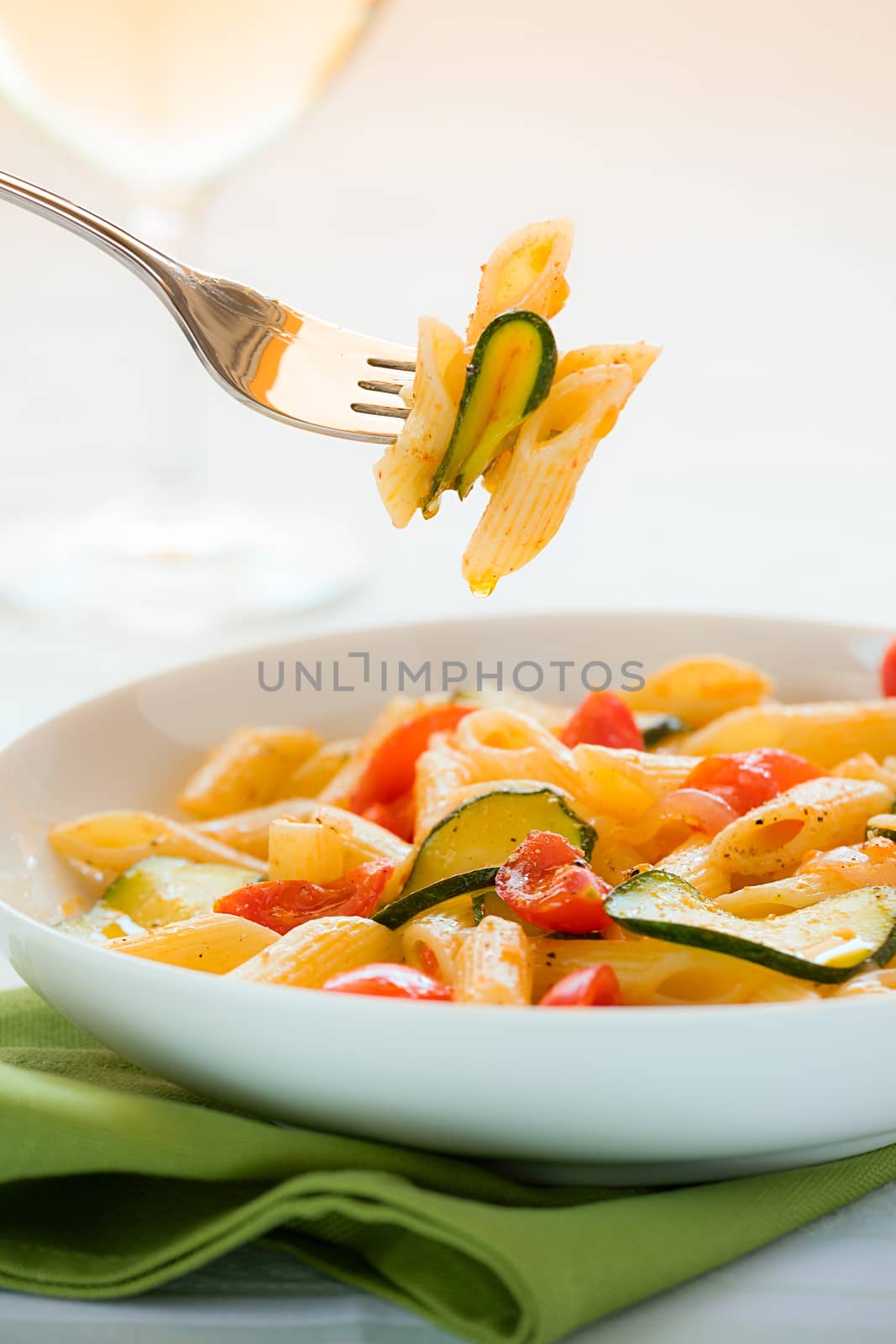 Traditional italian penne pasta with zucchini and cherry tomatoes seasoned with oil and pepper ready to eat