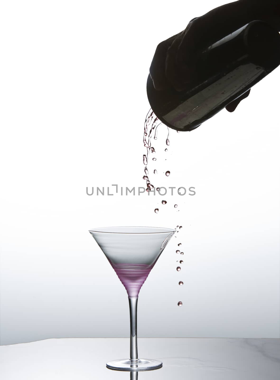 Cocktail being poured into martini glass by Njean