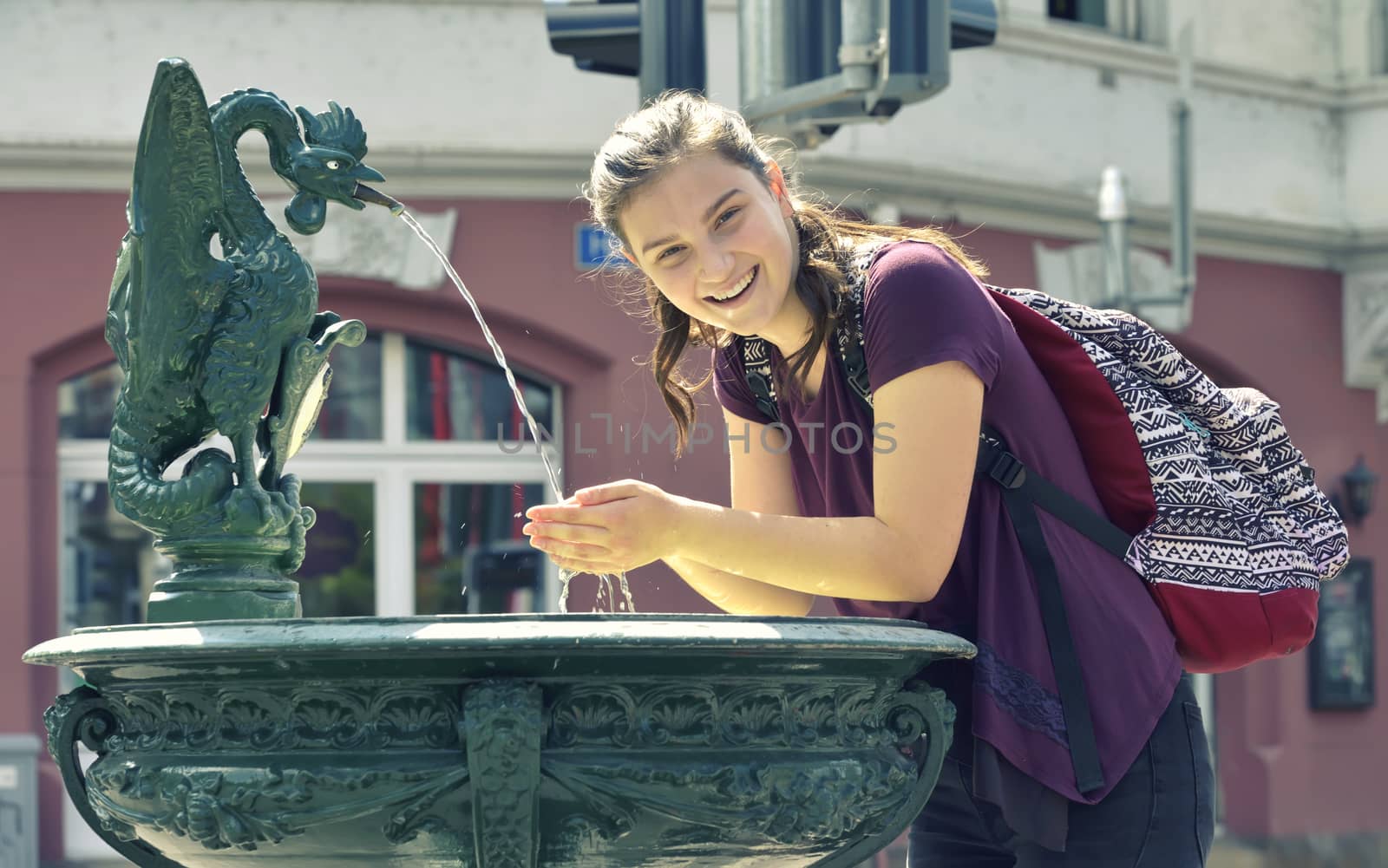 Young girl travel and drinking  water from the fountain