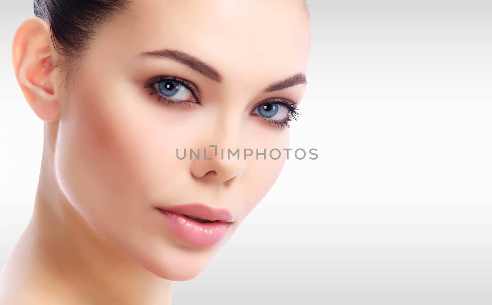 Pretty woman's face against a grey background with copyspace