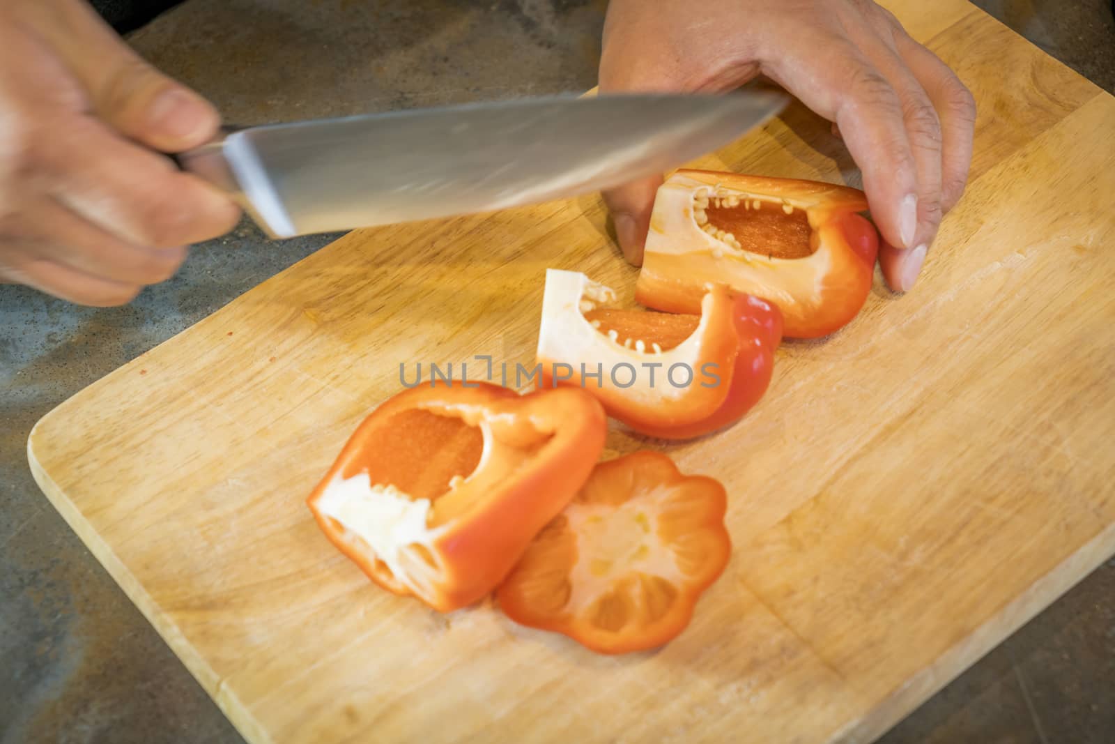 Chef cutting red bell pepper on wooden broad