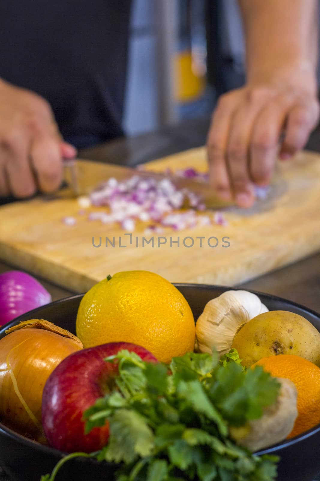 Fresh fruit in the kitchen with chef cutting onion to prepare food.