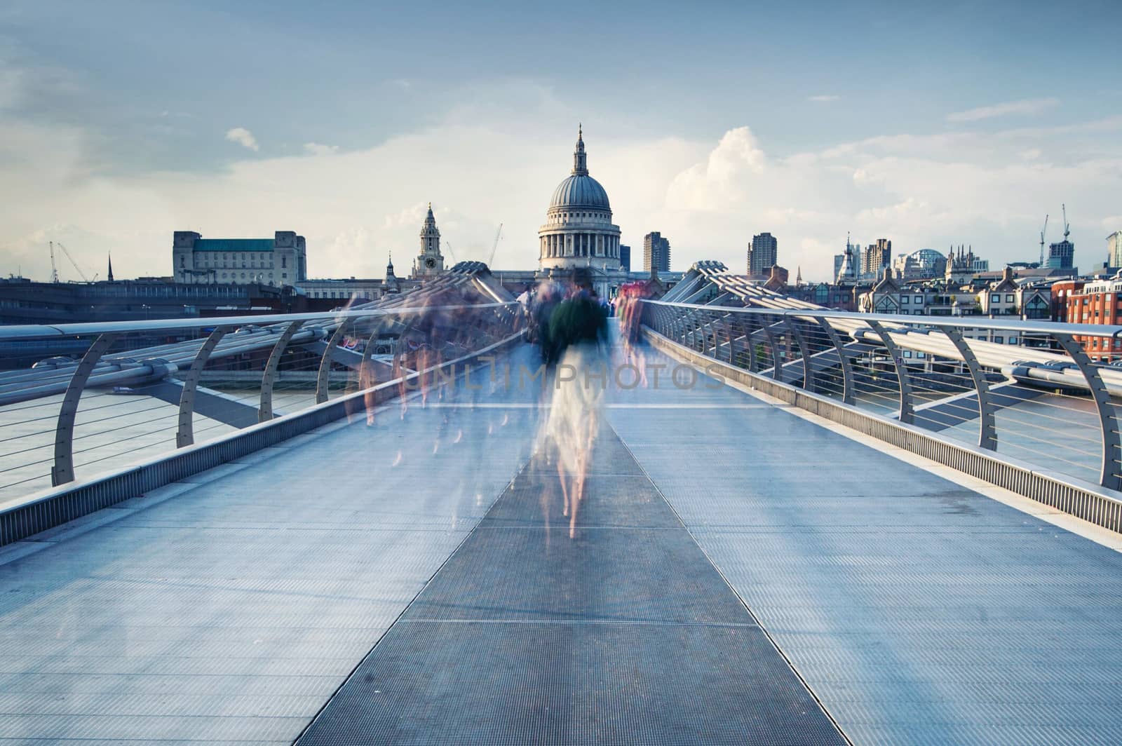 People walking over Millennium bridge at dusk.