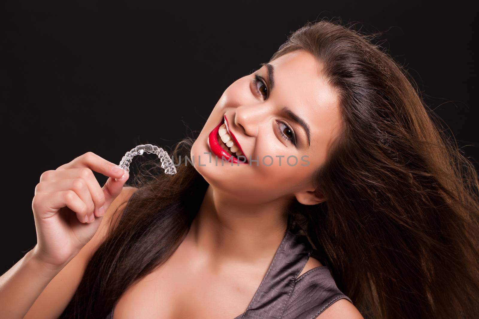 Young attractive smiling woman holding transparent denta bracesl on isolated studio background