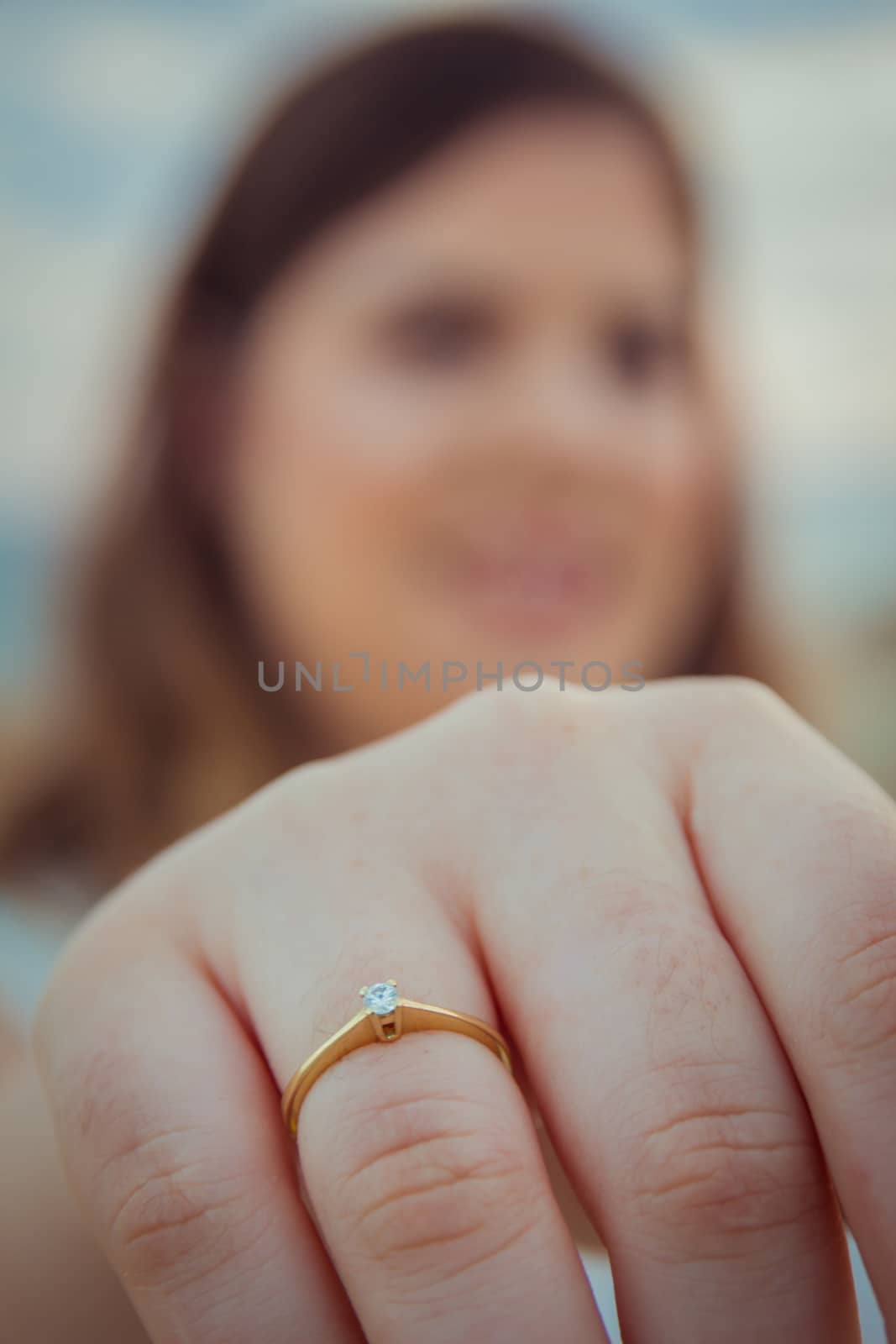 Happy woman shows off her new engagement ring on her finger. Closeup blur background.