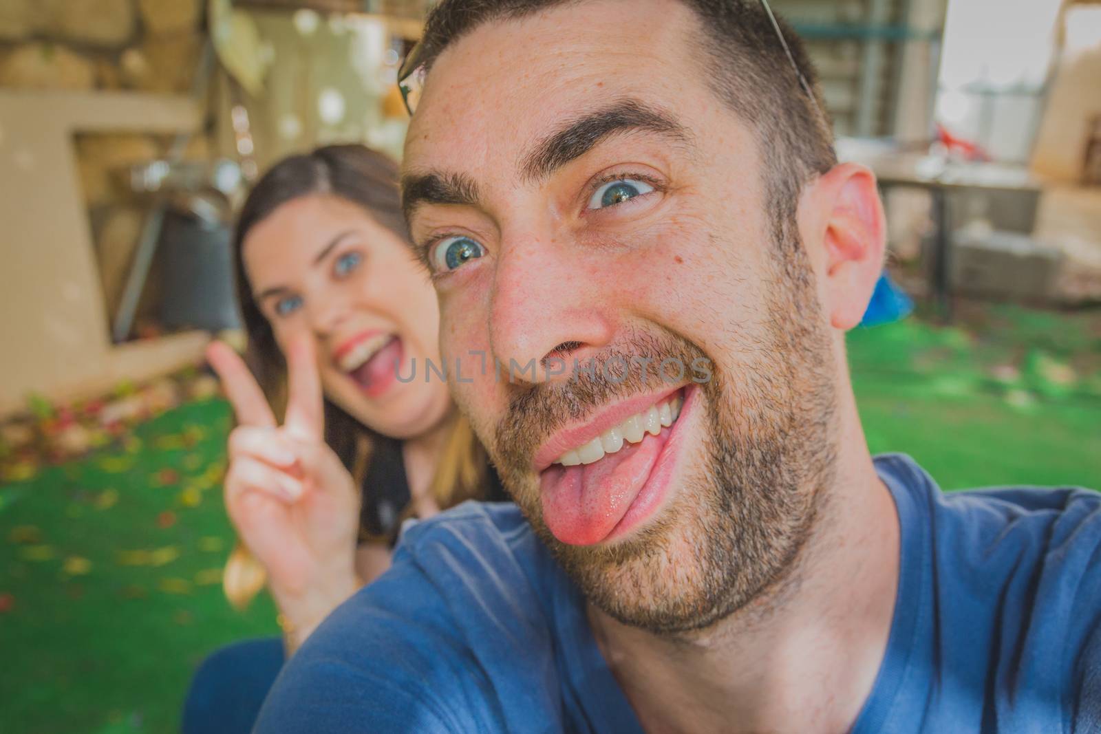 Young couple enjoying together in the backyard. They are smiling, laughing and making funny faces together.