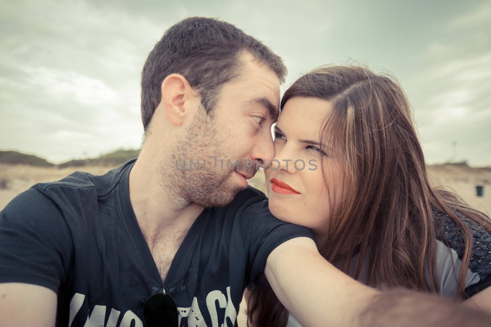 Young couple taking selfie with smartphone or camera at the beach.