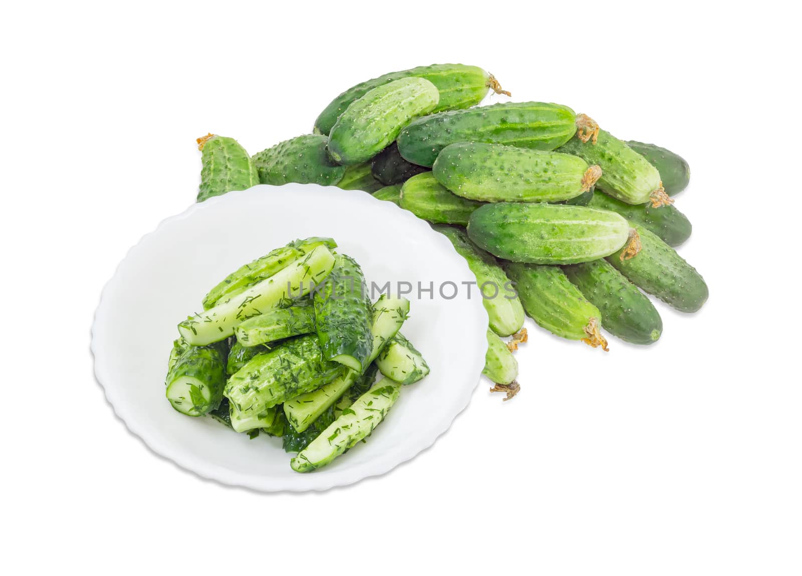 Lightly salted cucumbers on the white dish against of a pile of the freshly picked out cucumbers on a white background
