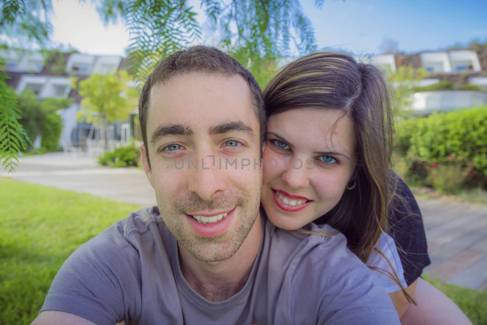 Happy couple taking selfie with smartphone or camera in the park.