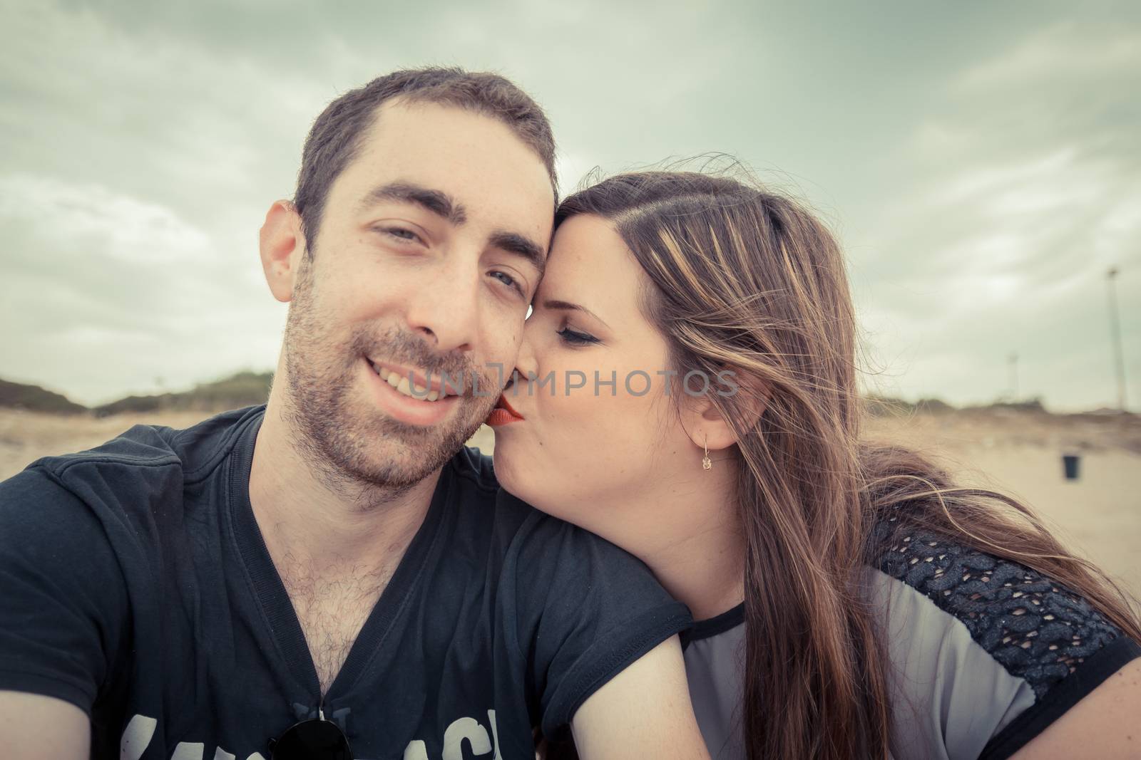 Young couple taking selfie with smartphone or camera at the beach.