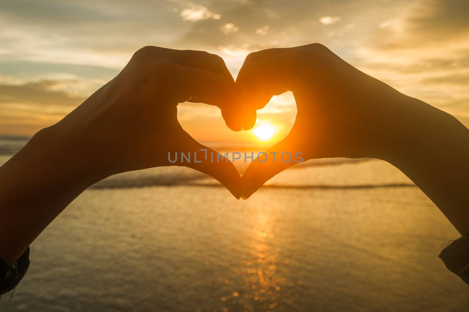 Hands make heart at sunset