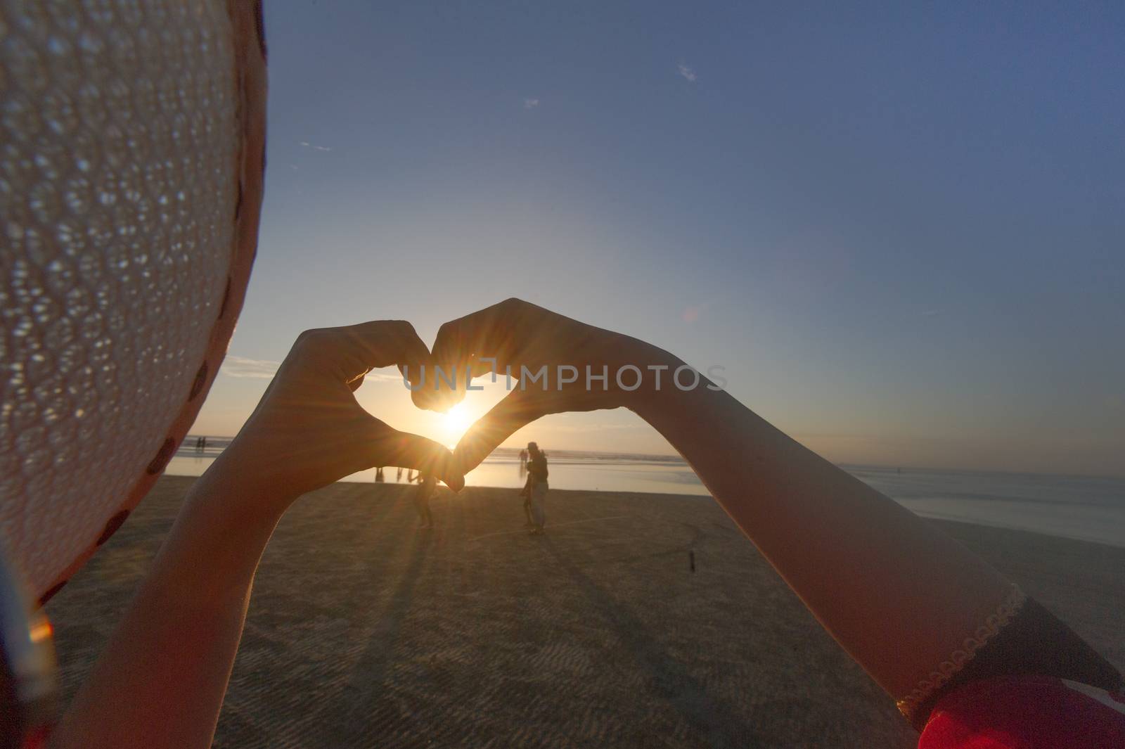 Hands make heart at sunset