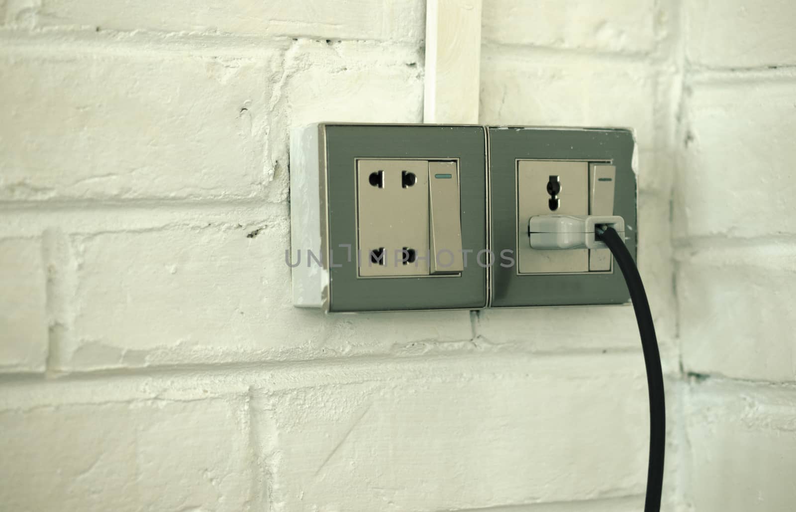 PLUGGED OLD SOCKET ON WHITE BRICK WALL by PrettyTG
