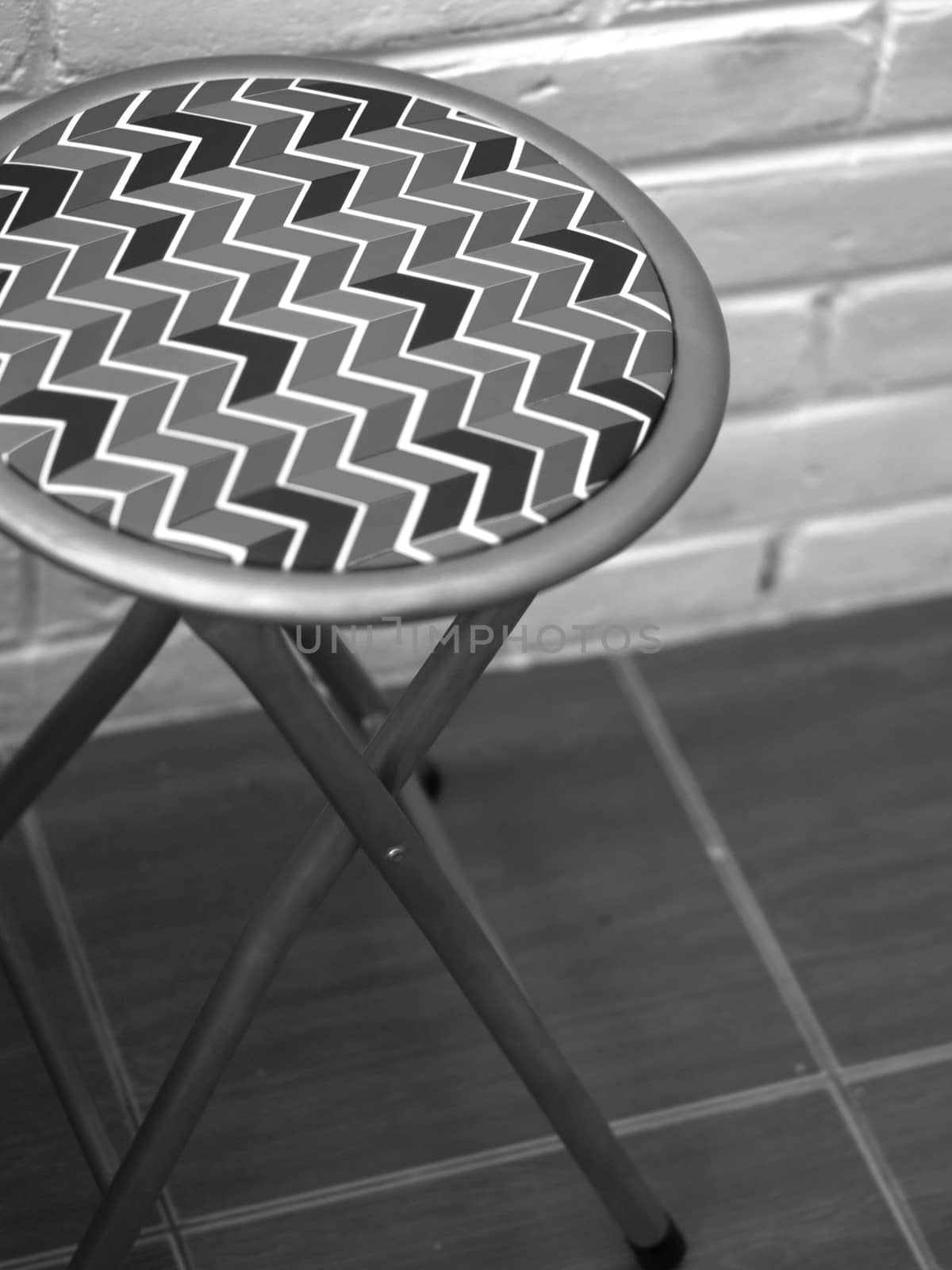 BLACK AND WHITE PHOTO OF STOOL WITH ZIG ZAG PATTERN LEATHER