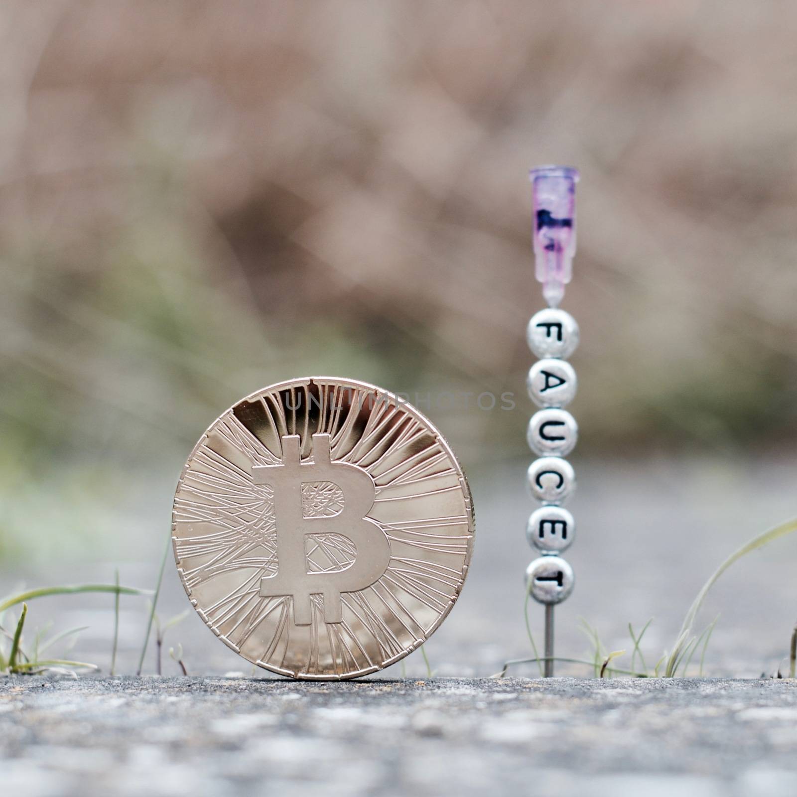 Digital currency physical gold bitcoin coin near faucet inscription on the needle.